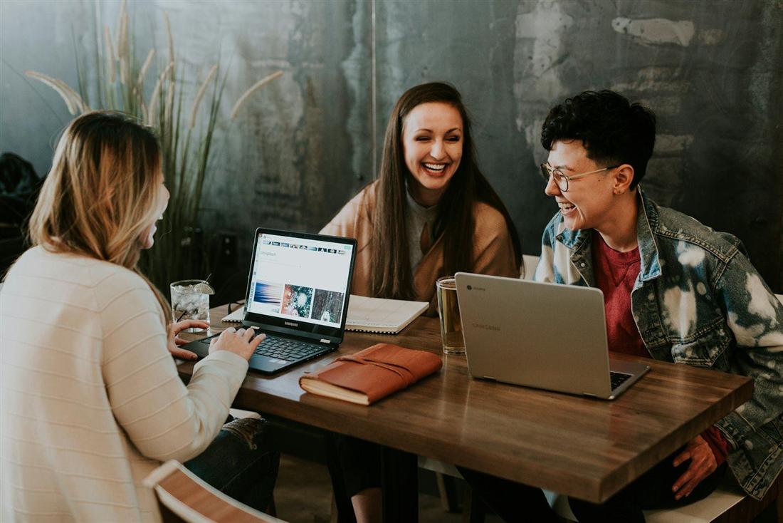 Tre colleghi discutono sorridendo davanti a un computer