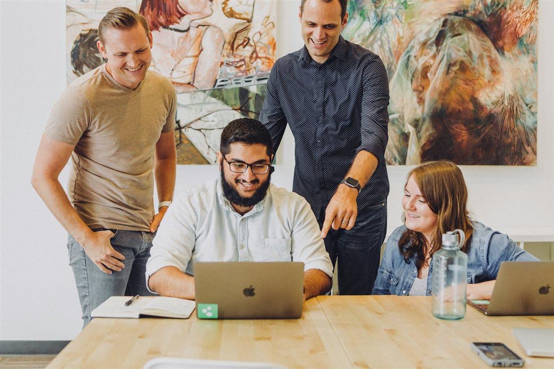 Un gruppo di lavoro sorridente attorno a un computer portatile